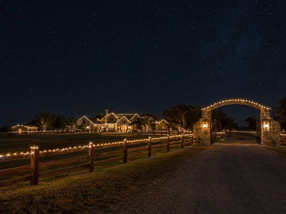 Ranch fence and stone gate lined with lights