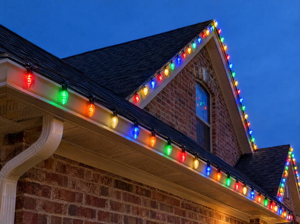 Roofline and gutters lined with multicolor C9 Christmas bulbs